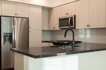 A kitchen with a stainless steel refrigerator and a microwave above the counter.